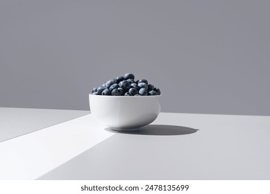 Blueberries in a white bowl on gray and white background - Powered by Shutterstock