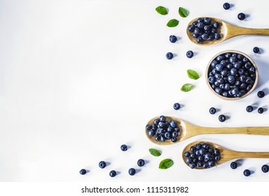 blueberries in a wooden bowl and spoons on a white background. the view from the top. blueberries flat lay. white background with blueberries. - Powered by Shutterstock