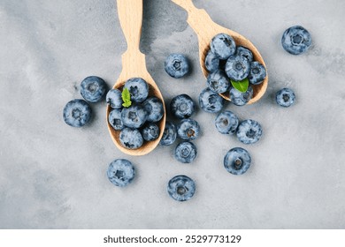 Blueberries in wooden spoons on grey background - Powered by Shutterstock