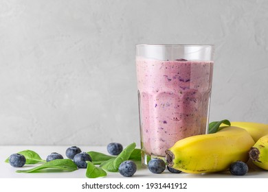 Blueberry, banana and spinach smoothie or milkshake in a glass with fresh fruits and berries. Healthy drink. close up
