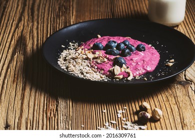 Blueberry Breakfast Smoothie Bowl. Fresh Berries, Rolled Oats, Toasted Hazelnut On Black Plate And Kefir In Glass Jar