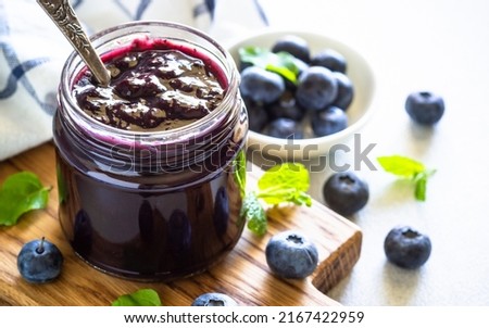 Blueberry jam in the glass jar with fresh berries.