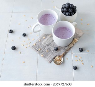 Blueberry And Oat Milk Smoothie In White Mugs On A Light Background. Top View