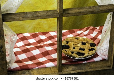 Blueberry Pie On Checked Table Cloth Cooling On Wood Framed Window Sill With Yellow Background