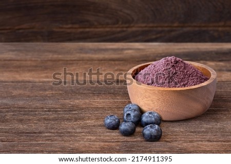 Blueberry powder in wooden bowl and fresh blueberry fruit isolated on wooden table background with copy space. 