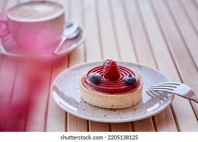 Blueberry And Raspberry Tart And Cappuccino In White Ceramic Cup On Wooden Table At The Terrace. Aesthetic Breakfast