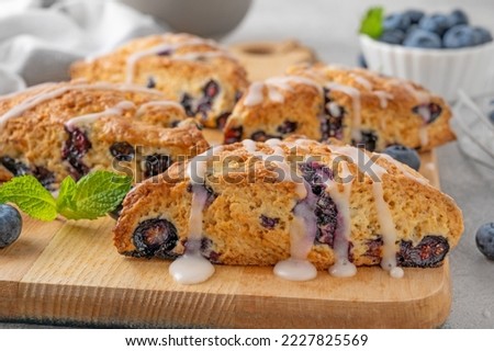 Blueberry scones with lemon glaze on top on a gray concrete background. Delicious breakfast