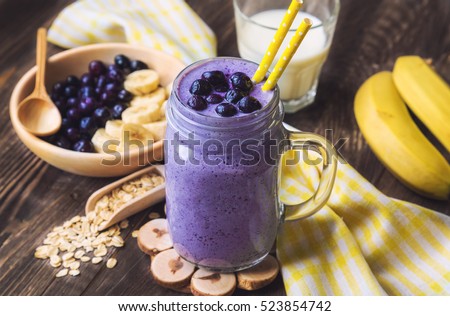 Blueberry smoothie with banana and oat flakes in jar on rustic wooden background. 