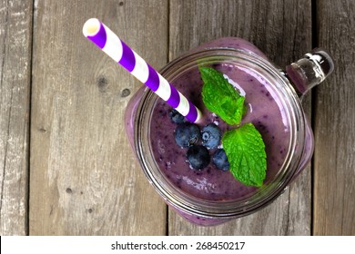 Blueberry Smoothie With Mint In Mason Jar Mug With Straw. Above View On Wood.