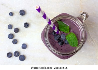 Blueberry Smoothie With Mint In Mason Jar Glass With Straw. Above View On White Marble.