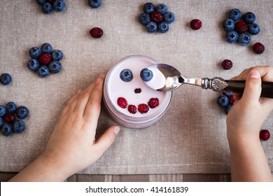 Blueberry yogurt with a smiling face. Child hands with yogurt. Top view