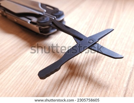 Blued metal tools in a multitool. Scissors close-up.