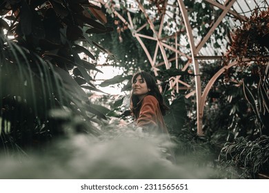 blue-eyed caucasian girl with long hair and beautiful earrings calm and relaxed looking at camera happy among the beautiful plants of the botanic garden, botanic garden christchurch, new zealand - Shutterstock ID 2311565651