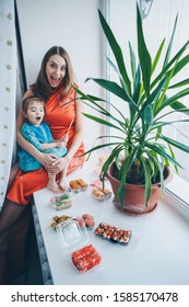 blue-eyed Caucasian woman and girl in traditional Chinese dress eating sushi sticks. Blonde and child in Japanese culture. concept of healthy food, Oriental cuisine