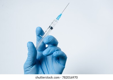 A Blue-gloved Hand Holds A Syringe