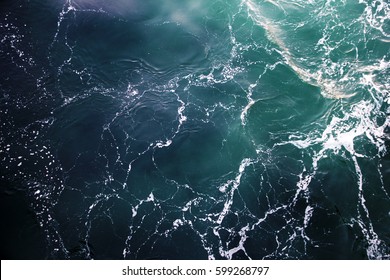 Blue-green waves on the surface of the ocean. Top view of the water.
