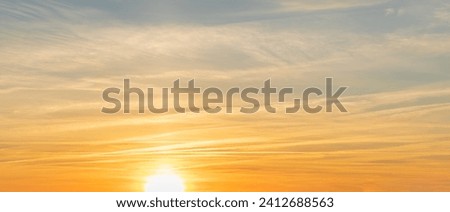 Blue-orange cloudy sky with the disk of the setting sun.