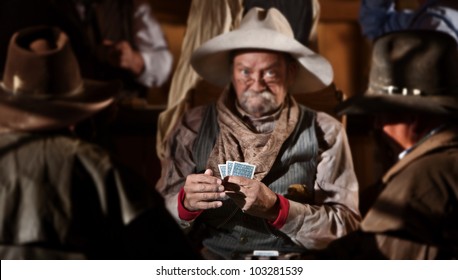 Bluffing card player in old American west saloon. Hands in focus.