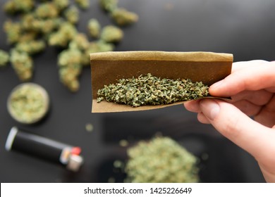 Blunt and Lighters. CBD and THC on buds in cannabis. Cannabis buds in hand on black background Background for Copy space. Herb grinder Fresh marihuana. Close up.