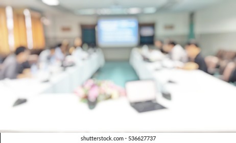 Blur Abstract Background Of Employees Meeting In Conference Room. Blurry View People Meet In Conference Room With Projector Screen. Defocus Teamwork Staffs Working In Meeting Room. Employee Brainstorm