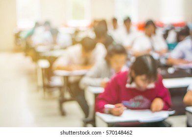 Blur Abstract Background Of Examination Room With Undergraduate Students Inside. Blurred View Of Student Doing Final Test In Exam Hall. Blurry View Of Study Chairs In Classroom Of University Or Campus