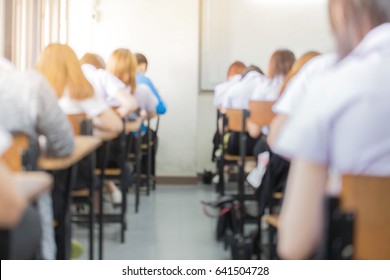 Blur Abstract Background Of Examination Room With Undergraduate Students Inside. Blurred View Student Doing Final Exam.university Study Uniform On Chairs In Classroom.