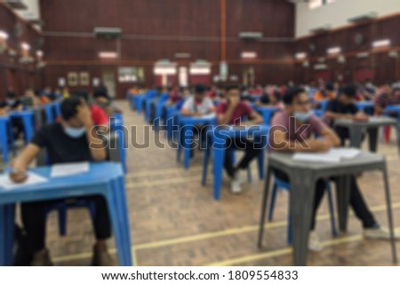 Blur abstract background of examination room with undergraduate students inside. Blurred view of student doing final test in exam hall.