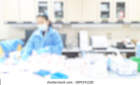 Blur Abstract Background Of Female Scientist Working In University Research Laboratory. Blurry View Of Lab Technologist Test Specimen In Science Room. Defocus Chemist Work In Laboratory In Hospital.