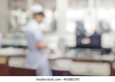 Blur Abstract Background Nurses In White Uniform Working Behind Nurse Station Counter In Patient's Wards Hospital.Blurry Interior Perspective View Staff Team On Duty In Charge Of Clinical Routine Job.