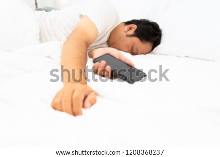 Blur addict man sleeping on home holding mobile phone in his hand in. Social media overuse ddiction and obsession concept.