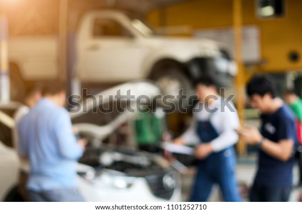 Blur background of auto repair service mechanic.\
Cars in garage of auto repair service shop with special repairing\
and technician car.