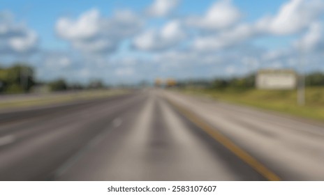 Blur Background of Empty highway under a clear blue sky with fluffy clouds and green trees lining the road in a peaceful setting. Defocused Image for Background.