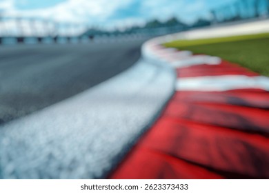 Blur Background of High Angle View of Curved Race Track Edge with Red and White Barrier Lines Under Clear Blue Sky. Defocused Image for Background.