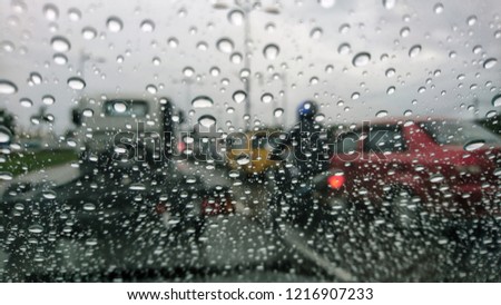 blur background of raindrops on windscreen, driving in rainy season.