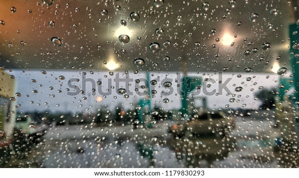 Blur background, Raindrops on the\
windshield in Petrol station, colorful bokeh at\
evening.