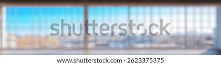 Blur Background of Spacious modern interior with large windows showcasing a vibrant city skyline on a bright sunny day. Defocused Image for Background.