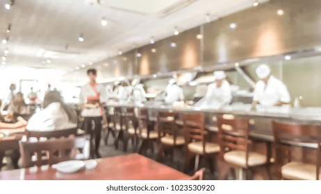 Blur Background Of Sushi Restaurant With Many Chef Making Sushi Behind The Sushi Bar. Traditional Japanese Cuisine And Small Business In Tokyo, Japan.