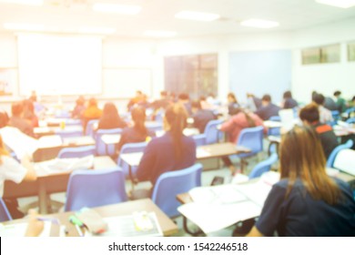 Blur Background Of University Students Does Quizzes, Test Or Studies From The Teacher In A Large Lecture Room. Students In Uniform Attending Exam Classroom Educational School.