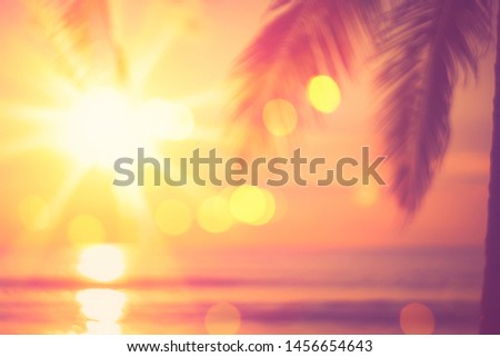 Blur beautiful nature green palm leaf on tropical sunset beach with bokeh light wave abstract background. Copy space of summer vacation and business travel concept. Vintage tone filter color style.