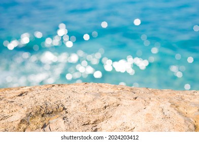 Blur blue sunlit sea background with stone rock in front - Shutterstock ID 2024203412