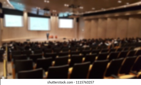 Blur Of Businessman Speaking In Front Of Stage With Projector Background While Participants Lecturing In The Convention Room In Hotel. Town Hall Meeting For Company Concept.