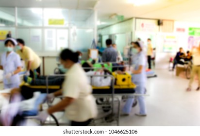 Blur Of Busy Nurse In Hospital Background, Medical Workers Moving Patient On Gurney Through Hospital Corridor Into An Accident & Emergency Ward.