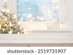 Blur Christmas tree and decorated window interior background with wooden table top for product display in front