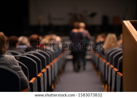 Blur defocus texture, background for design. Spectators in the theater sit on chairs before the performance