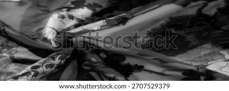 Blur of a delicate floral pattern in grayscale tones, highlighting the intricate texture and fine mesh overlay. The fabric folds create dynamic light and shadow contrasts, offering an elegant aestheti
