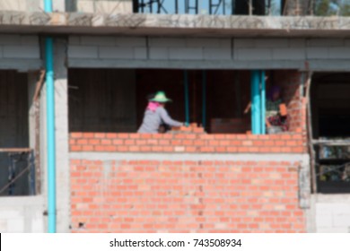 Blur Of  Female Worker Bricklayer Laying Brick A Wall Construction In Industrial  Building Site