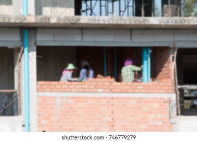 Blur Of  Female Worker Bricklayer Laying Brick A Wall Construction In Industrial  Building Site