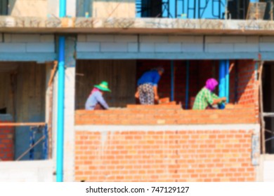 Blur Of  Female Worker Bricklayer Laying Brick A Wall Construction In Industrial  Building Site