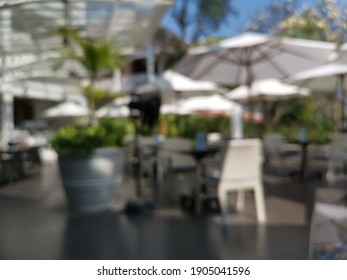 Blur focus of Cafe tables and chairs outside with big white umbrella and plant