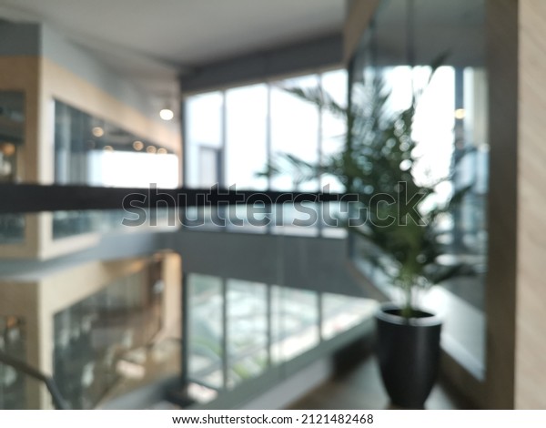 Blur focus of corporate office in minimalist\
modern design, office work stations and planter pot with hall way\
area in background